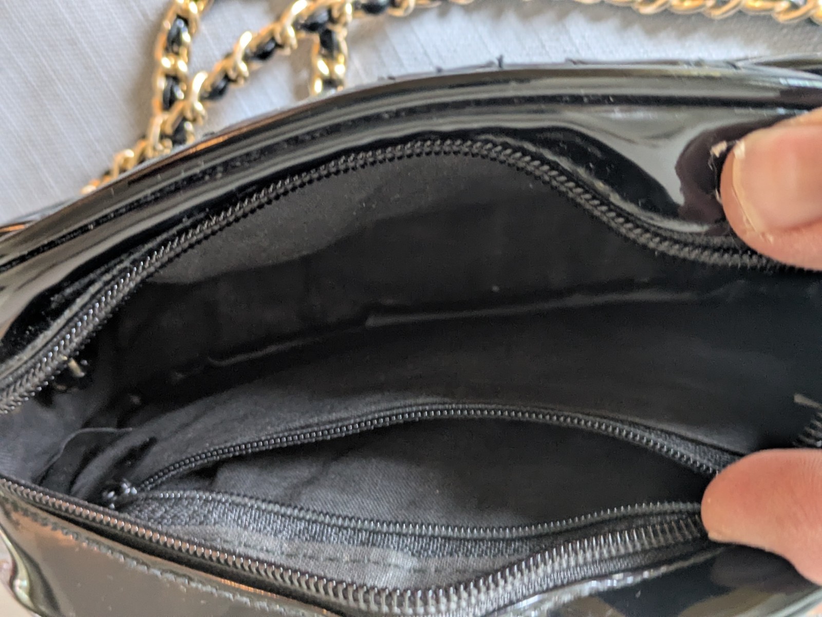 Black Patent Leather Oval Crossbody Bag. Goldtone chain handle with black accent