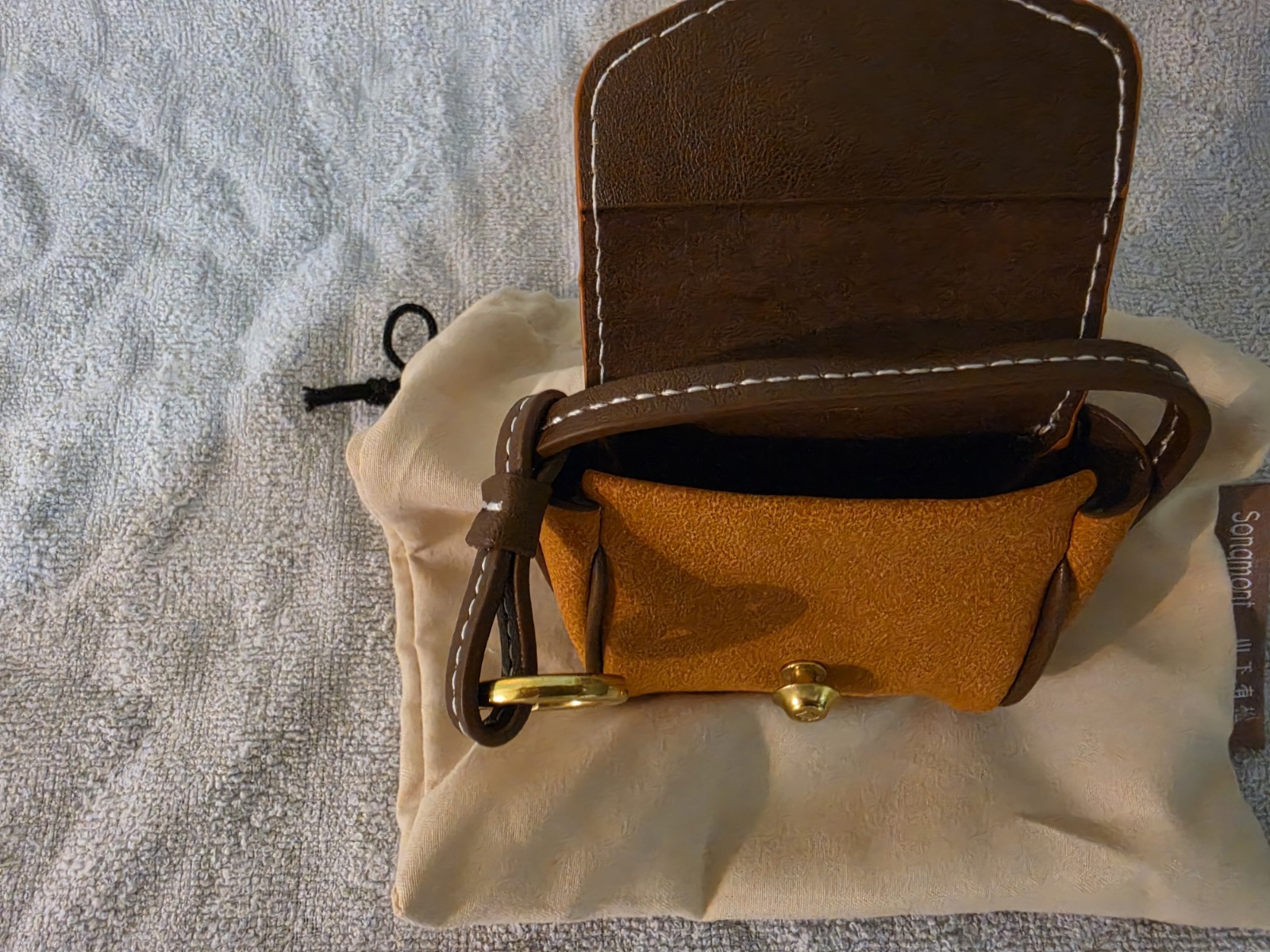 Songmont Brown earbud case with dust Bag.