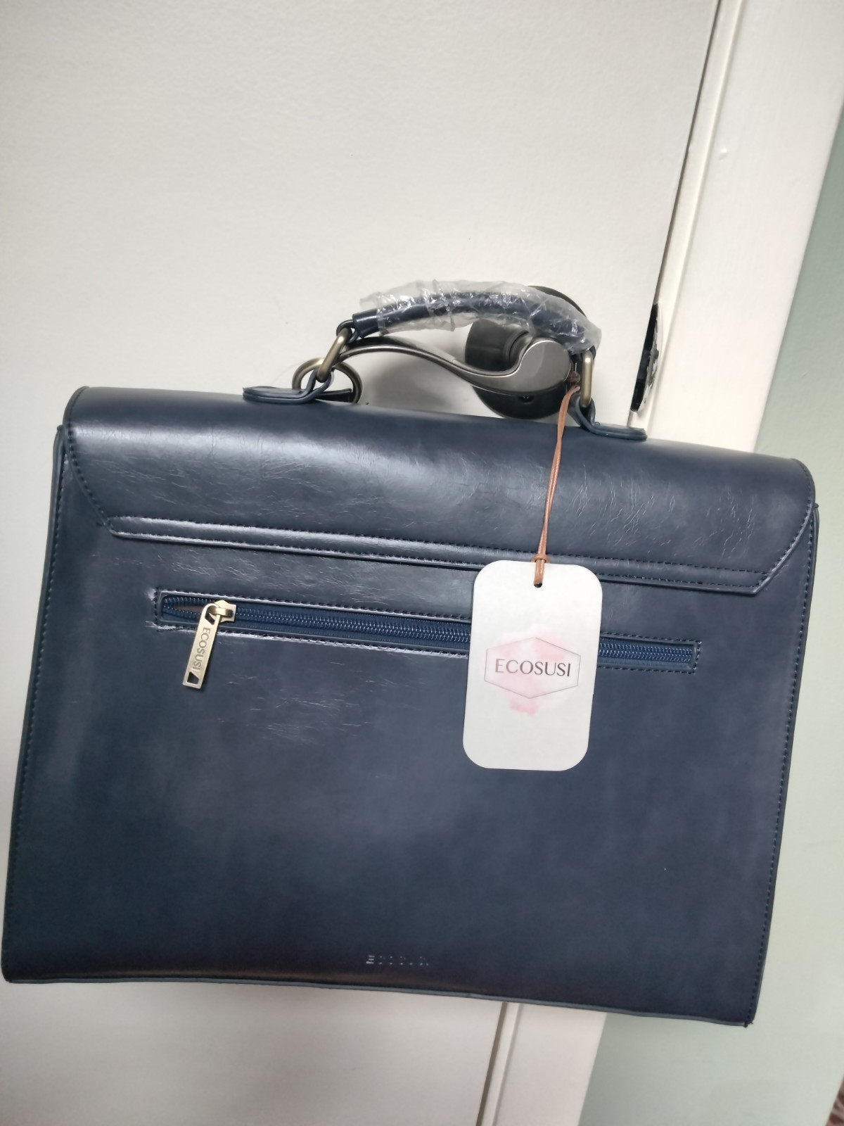 ECOSUSI briefcase features vegan leather construction and a protective handle…