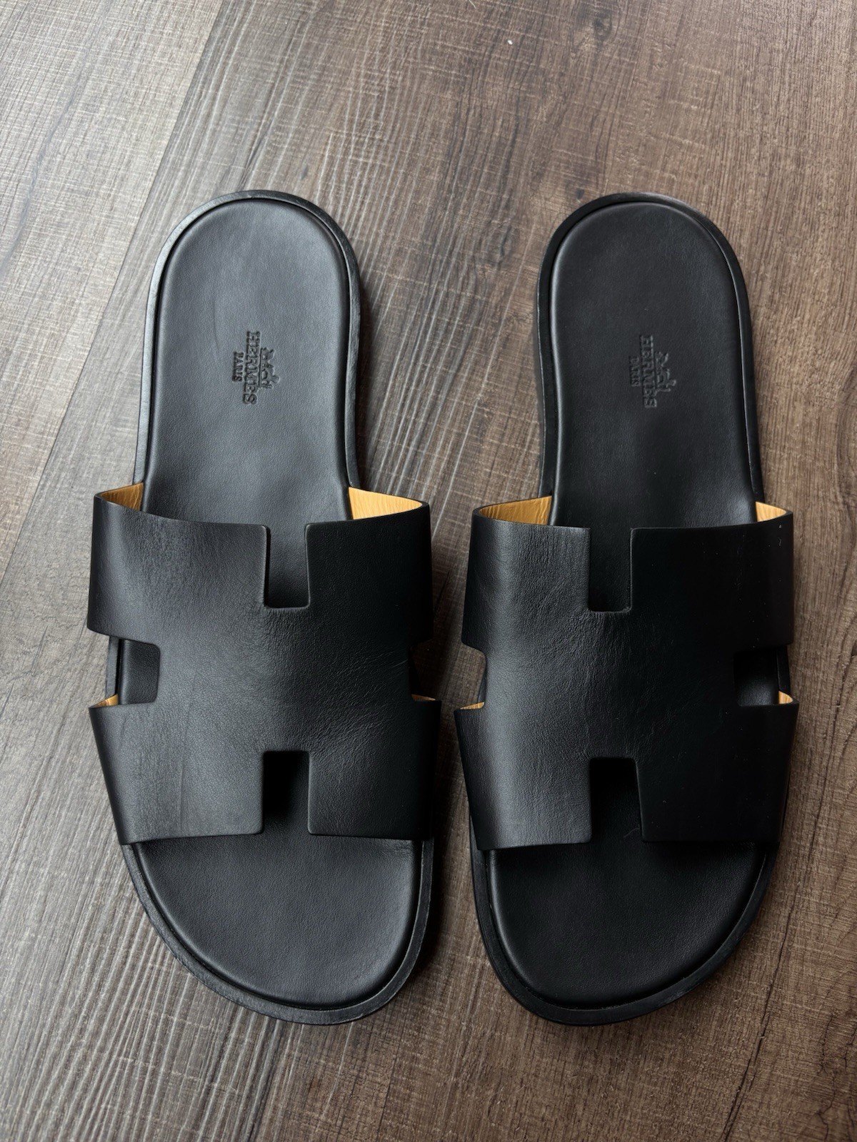 These are Hermès Oran sandals in black Box calfskin leather.