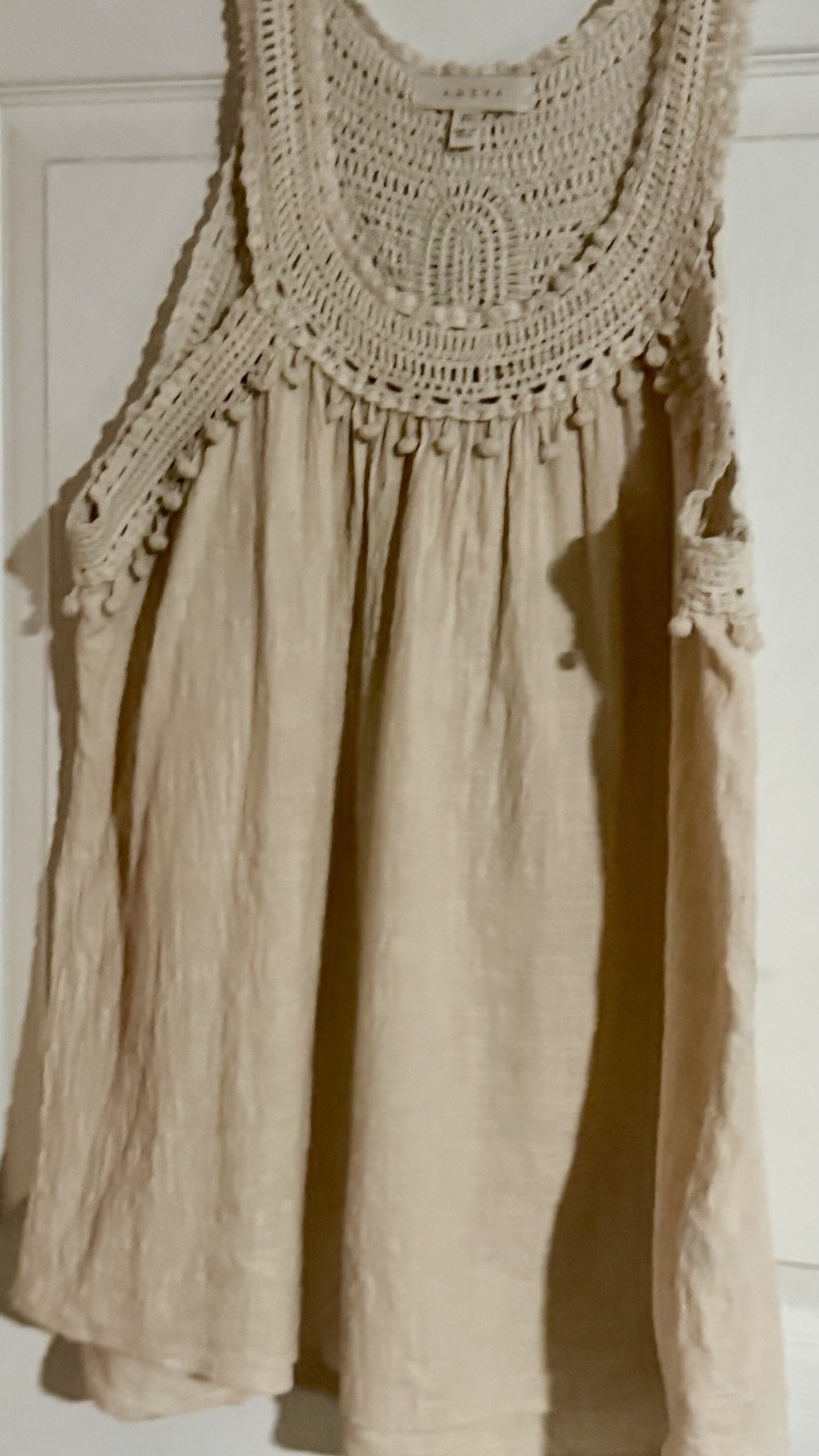 Adiva cream sleeveless top featuring a distinctive crochet yoke and pom-pom trim