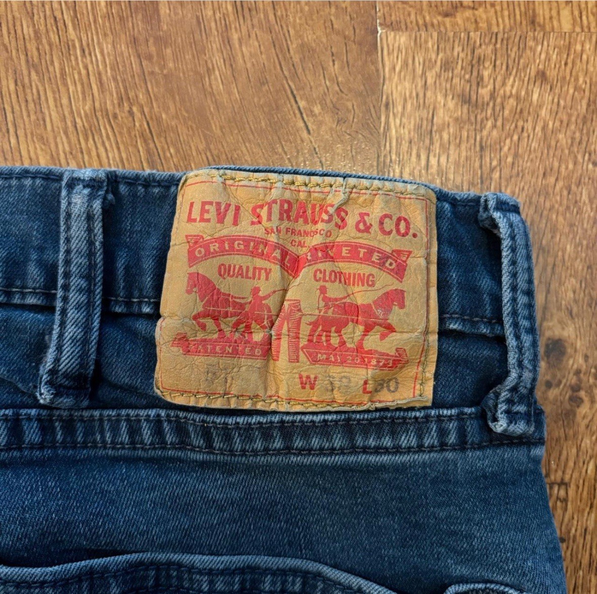 faded Levi’s 514 blue jeans size 38×30 with distressed areas, straight-leg