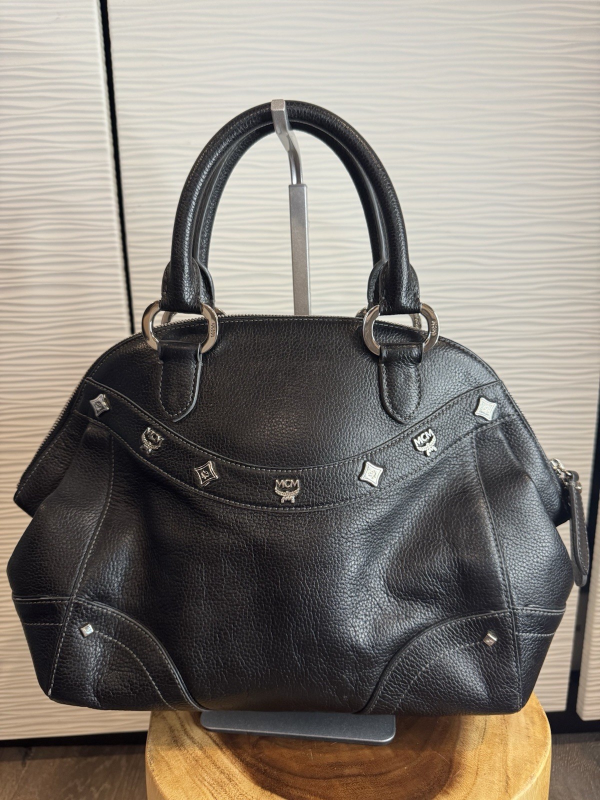 Black MCM Alda satchel with studded logo accents and structured handles.