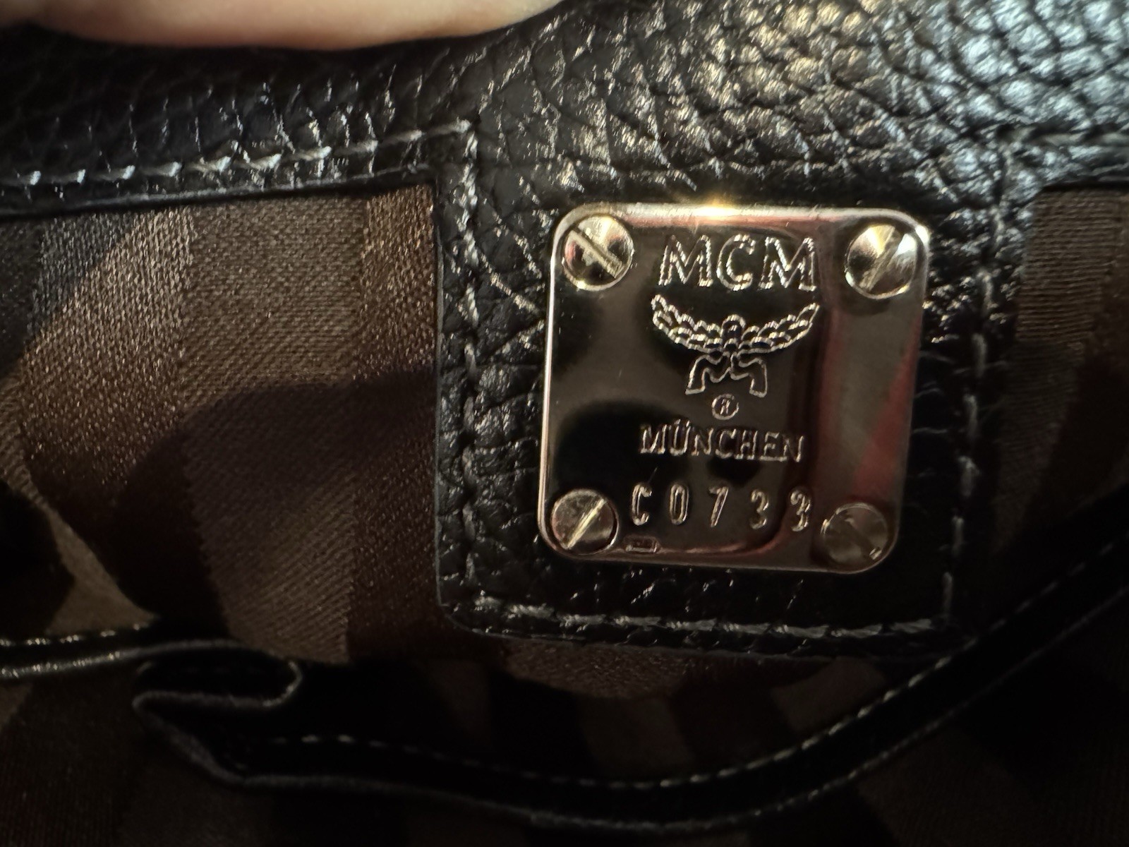 Black MCM Alda satchel with studded logo accents and structured handles.