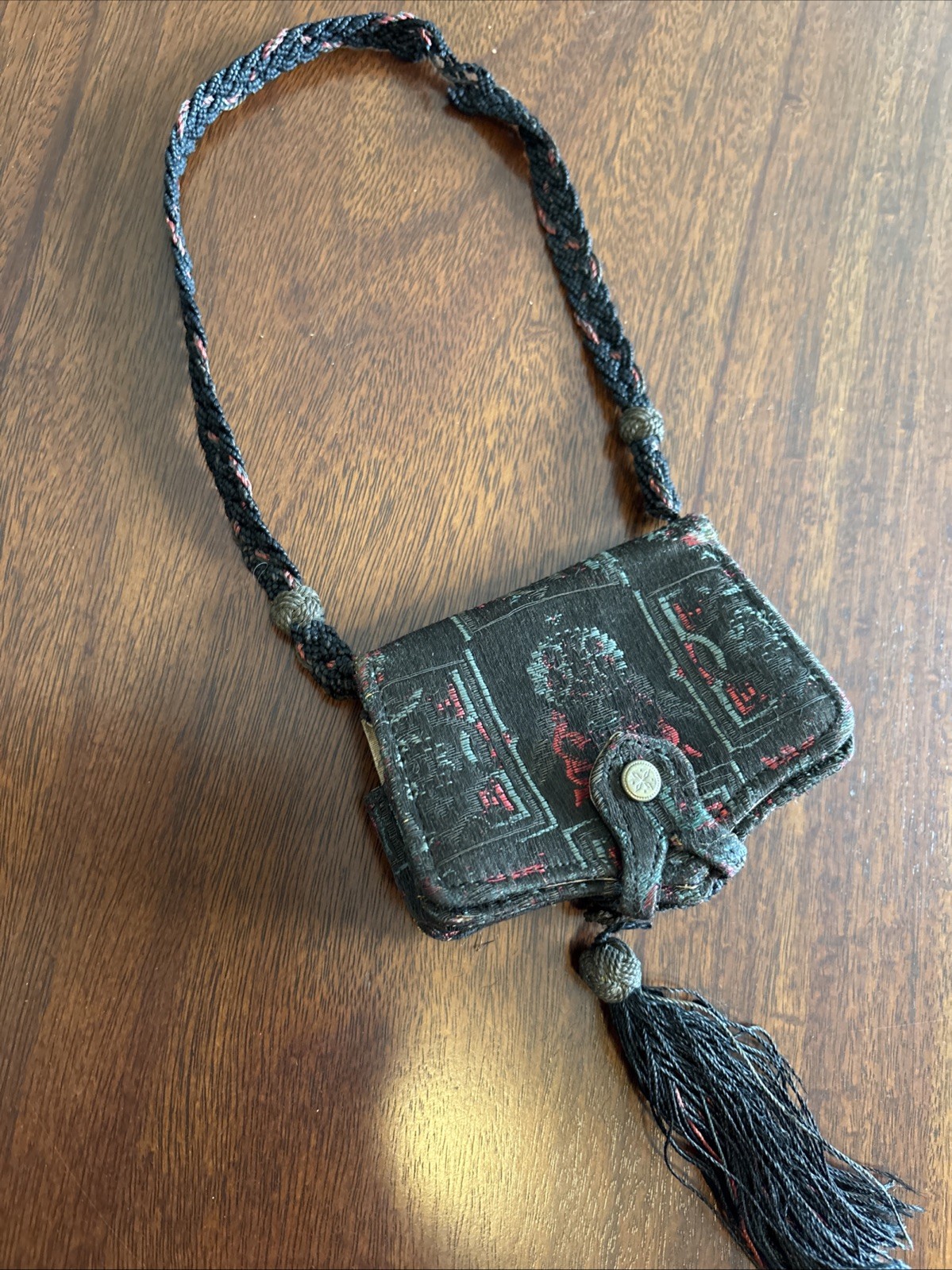 vintage, small tapestry purse with a dark woven pattern and a braided strap.