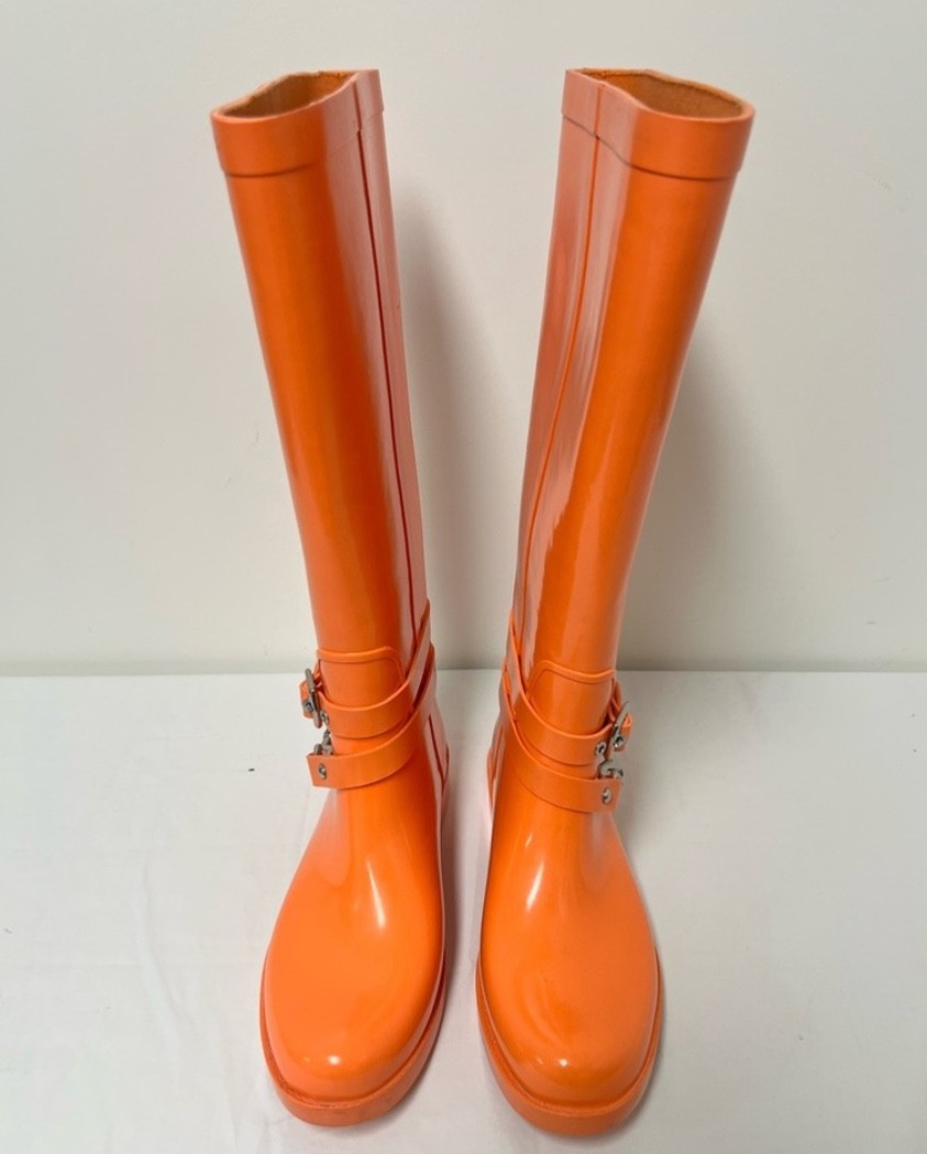 These are authentic Coach Lori tall rain boots in a bold orange color featuring