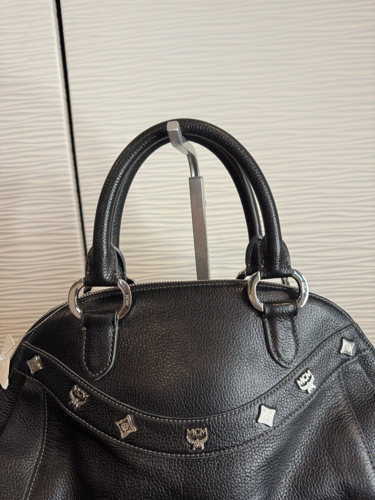 Black MCM Alda satchel with studded logo accents and structured handles.