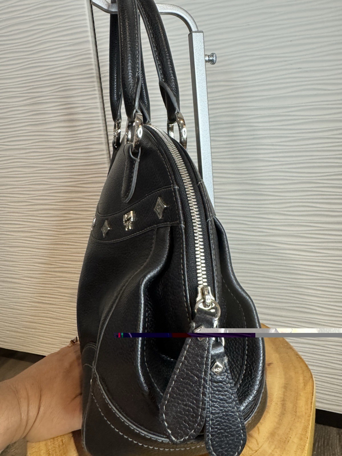 Black MCM Alda satchel with studded logo accents and structured handles.