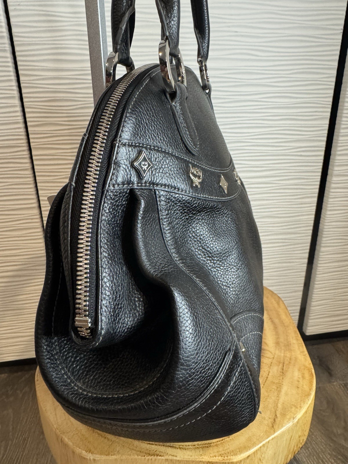 Black MCM Alda satchel with studded logo accents and structured handles.