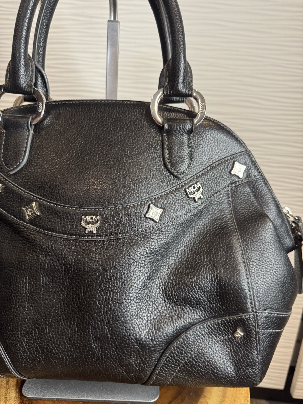 Black MCM Alda satchel with studded logo accents and structured handles.