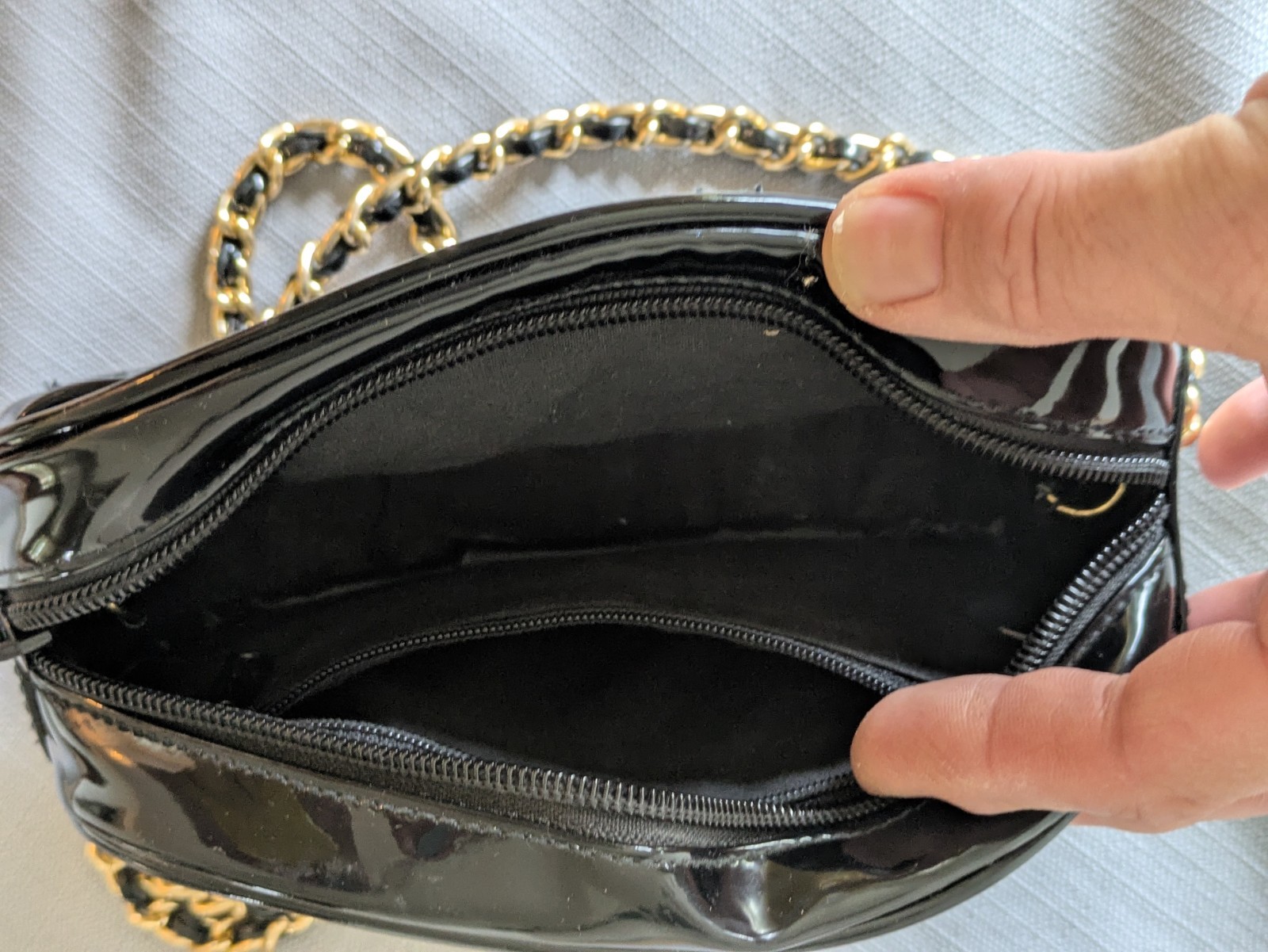 Black Patent Leather Oval Crossbody Bag. Goldtone chain handle with black accent