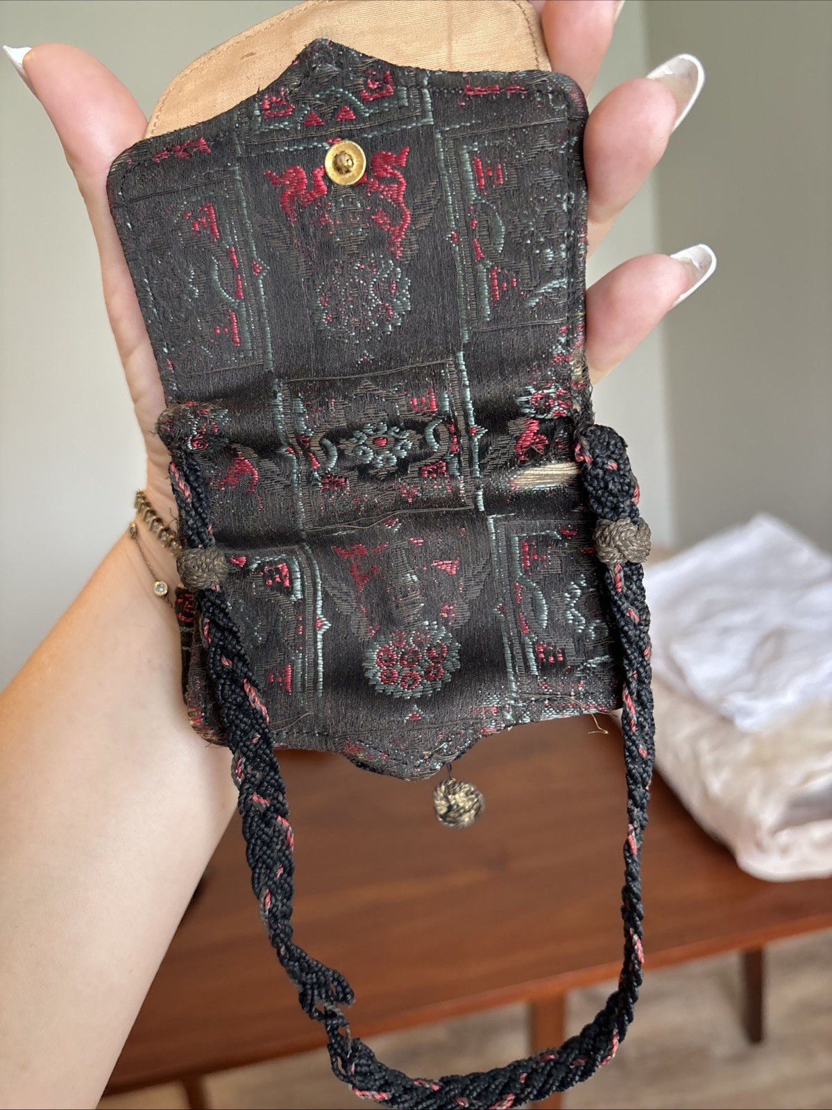 vintage, small tapestry purse with a dark woven pattern and a braided strap.