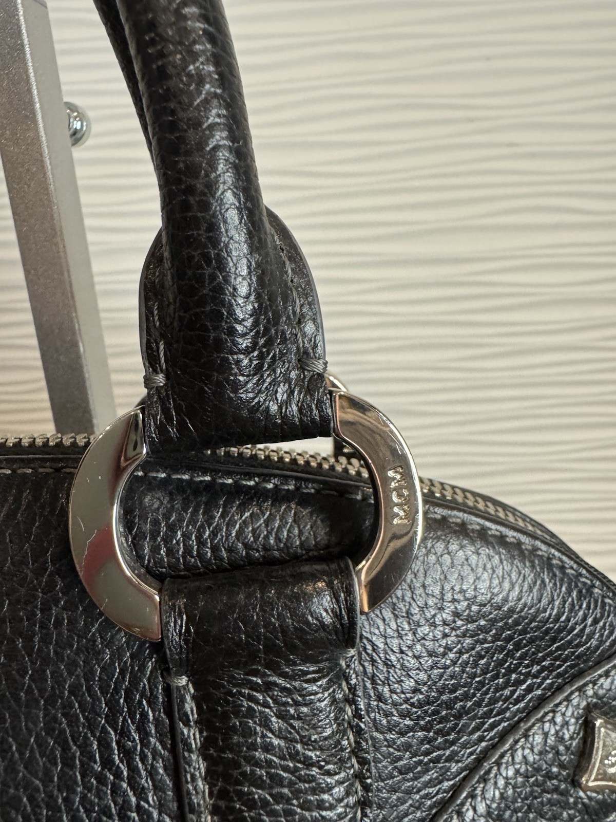 Black MCM Alda satchel with studded logo accents and structured handles.